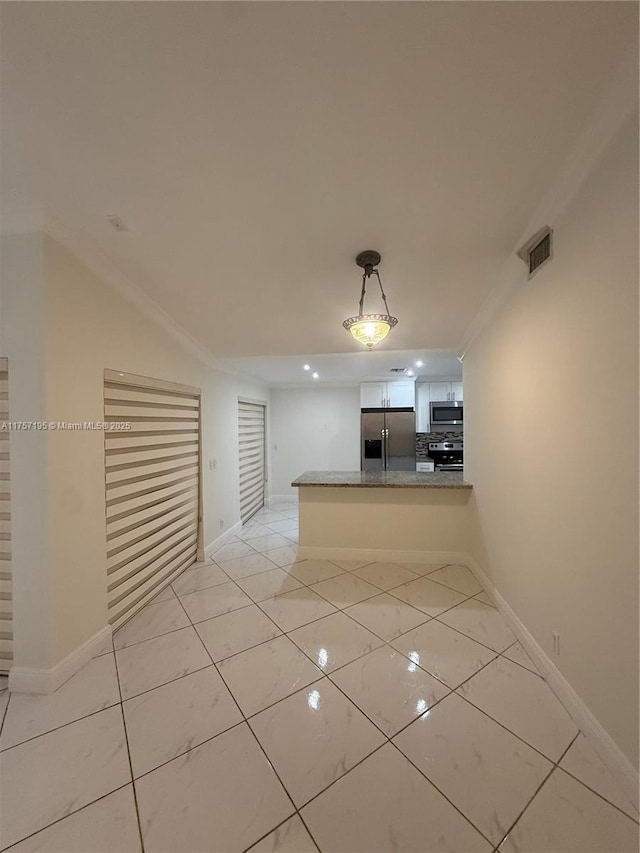 kitchen with a peninsula, baseboards, appliances with stainless steel finishes, and hanging light fixtures