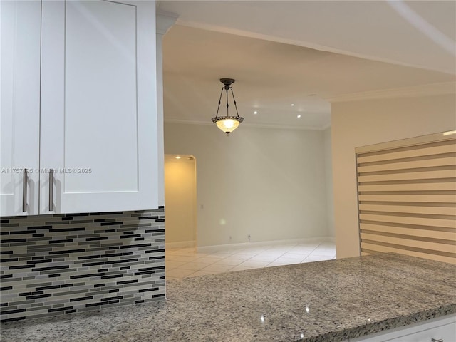 kitchen featuring white cabinetry, light stone counters, crown molding, and light tile patterned flooring