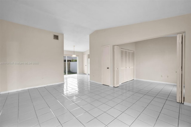 empty room featuring lofted ceiling, light tile patterned floors, baseboards, and visible vents