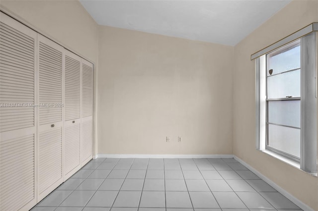 unfurnished bedroom featuring a closet, baseboards, and light tile patterned floors