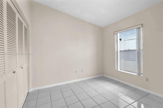 unfurnished bedroom with baseboards, a closet, and light tile patterned flooring