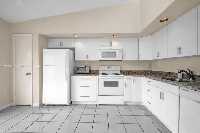 kitchen with light tile patterned floors, white cabinetry, a sink, dark stone countertops, and white appliances