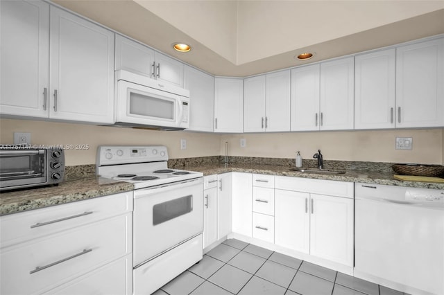 kitchen featuring light tile patterned floors, white appliances, a sink, and white cabinetry