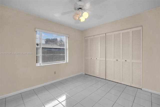 unfurnished bedroom with a closet, tile patterned floors, a ceiling fan, and baseboards