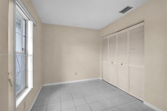 unfurnished bedroom featuring light tile patterned floors, baseboards, visible vents, and a closet