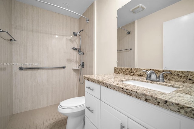 bathroom with toilet, tile patterned floors, tiled shower, and vanity