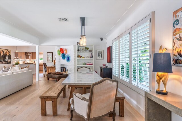 dining room featuring visible vents, light wood finished floors, and a fireplace