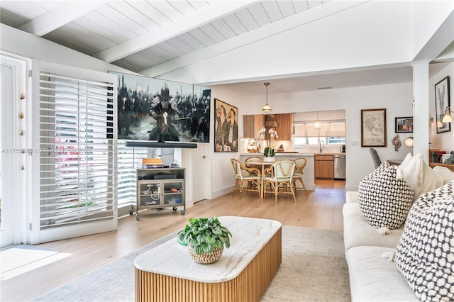 living area featuring lofted ceiling with beams and light wood-type flooring
