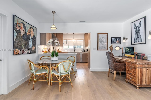 dining room featuring baseboards, light wood-type flooring, and visible vents