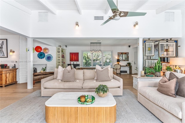 living room featuring light wood finished floors, beam ceiling, and visible vents