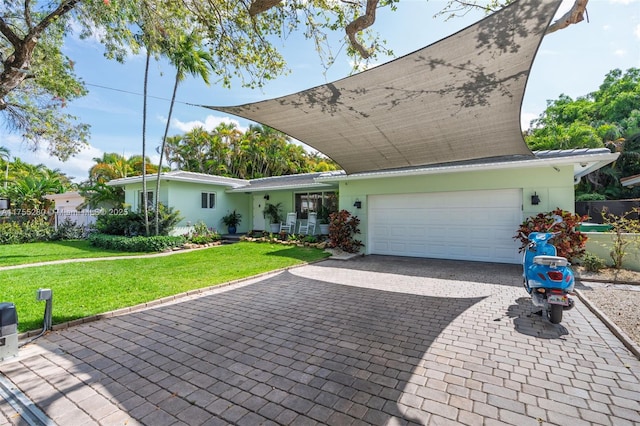 ranch-style house featuring an attached garage, stucco siding, decorative driveway, and a front yard