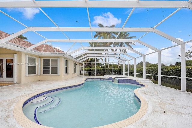 view of pool featuring glass enclosure, a pool with connected hot tub, and a patio