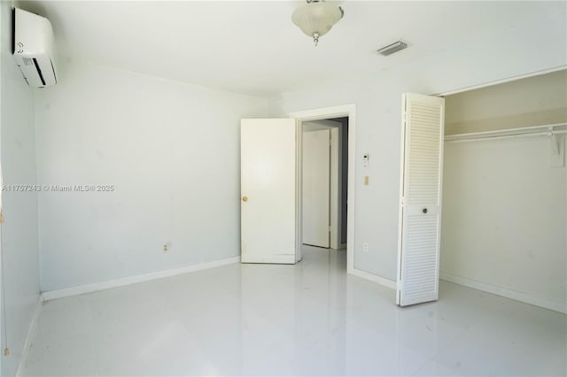 unfurnished bedroom featuring visible vents, baseboards, an AC wall unit, and a closet