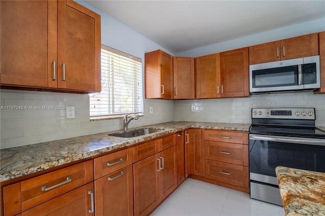 kitchen with backsplash, stone countertops, appliances with stainless steel finishes, and a sink