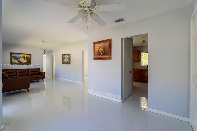 interior space with a ceiling fan, light tile patterned floors, visible vents, and baseboards