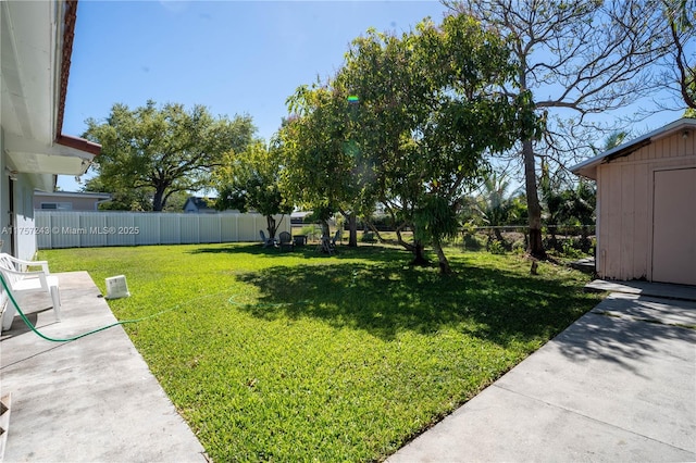 view of yard featuring an outbuilding, a fenced backyard, a shed, and a patio