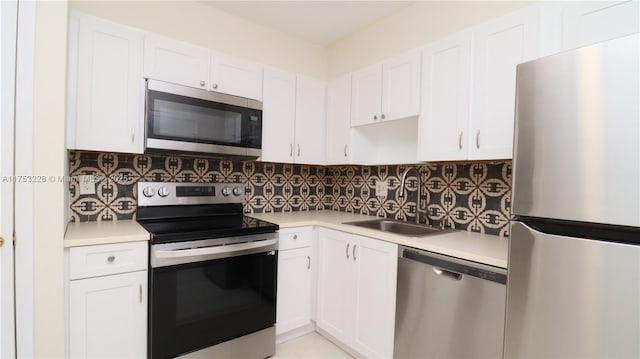 kitchen with appliances with stainless steel finishes, white cabinets, and backsplash