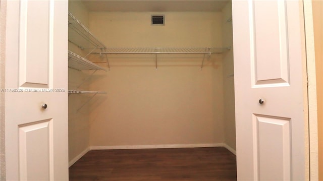 spacious closet featuring dark wood-type flooring and visible vents