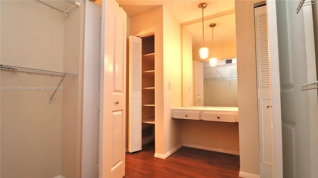 walk in closet featuring dark wood-style flooring and built in study area