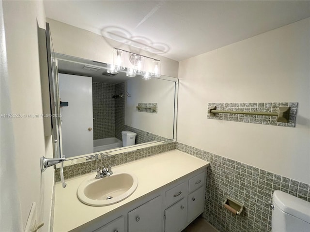 bathroom with toilet, shower / washtub combination, tile walls, and vanity