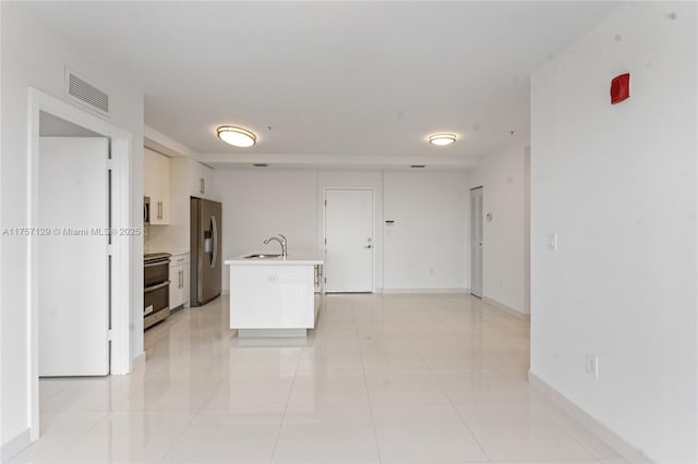 kitchen with visible vents, stainless steel appliances, light countertops, a sink, and light tile patterned flooring