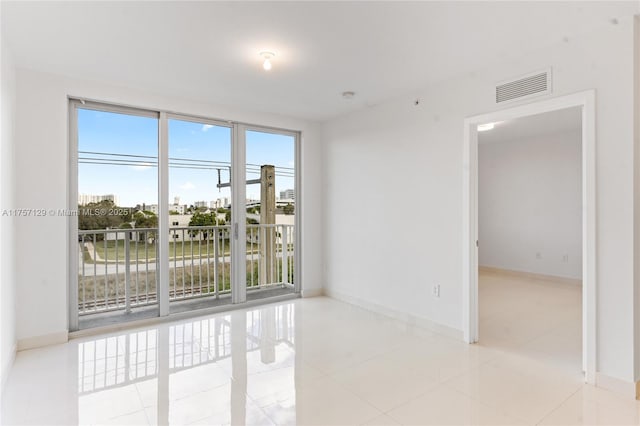 empty room with visible vents, baseboards, and tile patterned floors