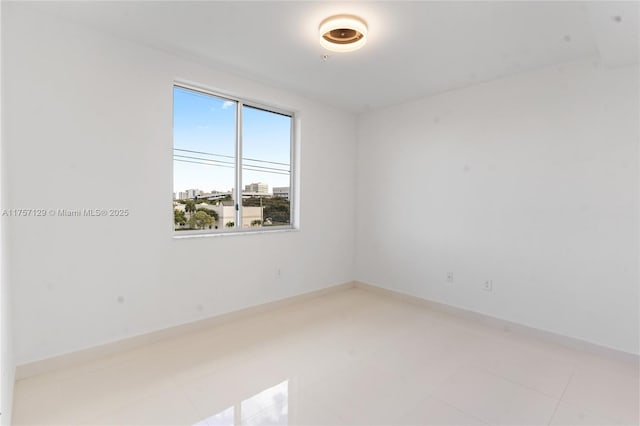 spare room with light tile patterned flooring and baseboards