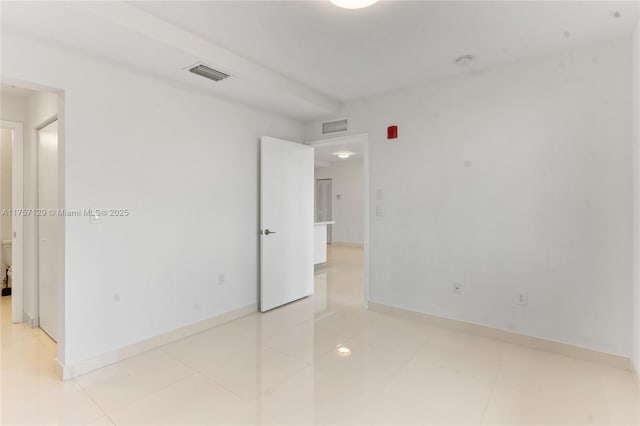 empty room with light tile patterned floors, baseboards, and visible vents