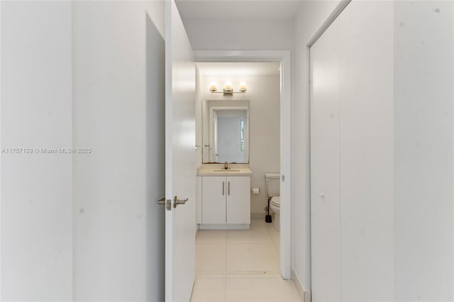 hallway featuring light tile patterned floors and a sink