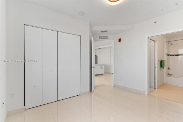 unfurnished bedroom featuring baseboards, visible vents, a closet, and light tile patterned flooring