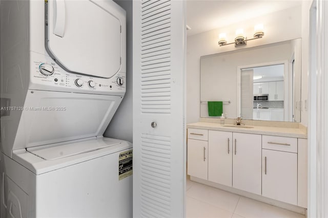 laundry area with light tile patterned floors, laundry area, stacked washing maching and dryer, and a sink