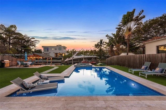view of swimming pool featuring a patio, a pool with connected hot tub, fence, and a lawn