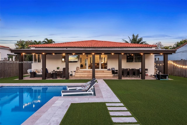 back of house with a fenced in pool, a patio area, a fenced backyard, and an outdoor hangout area