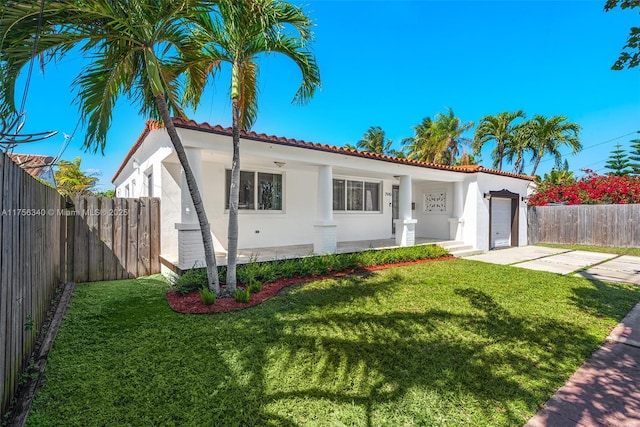 mediterranean / spanish house featuring stucco siding, driveway, a front lawn, a tile roof, and a garage