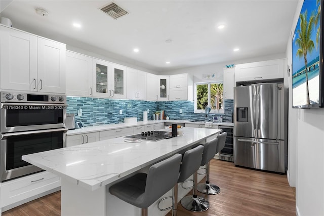 kitchen with visible vents, beverage cooler, stainless steel appliances, a breakfast bar area, and backsplash
