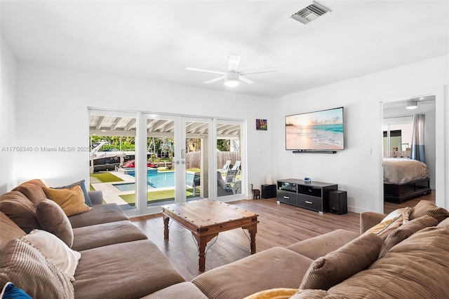 living area with french doors, a ceiling fan, visible vents, and light wood finished floors