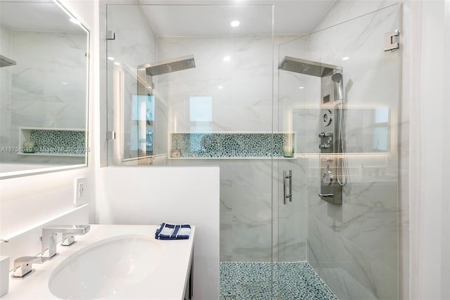 full bath featuring a marble finish shower and vanity