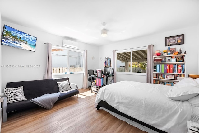 bedroom featuring wood finished floors and a wall unit AC