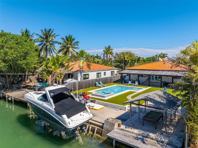 exterior space with a pool with connected hot tub, a fenced backyard, boat lift, and a patio area
