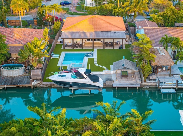 pool with a water view, a patio area, boat lift, and a dock