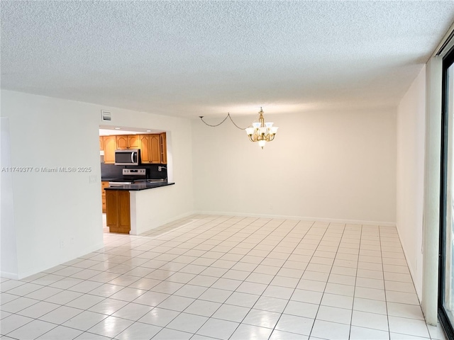 spare room with an inviting chandelier, light tile patterned flooring, baseboards, and a textured ceiling