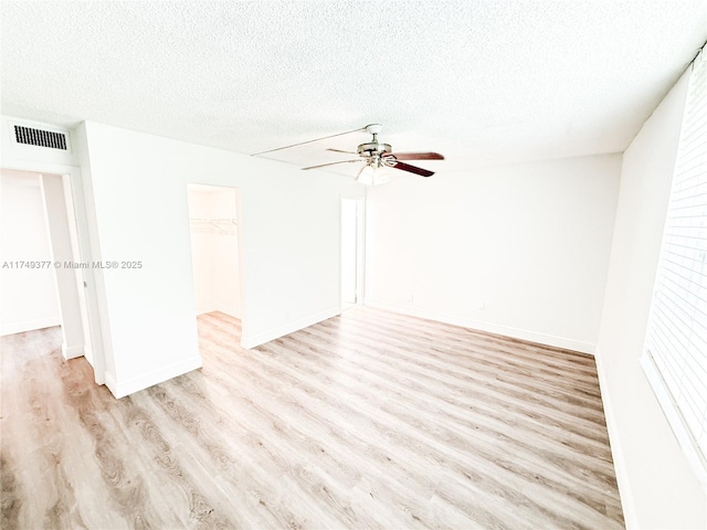 spare room with visible vents, a textured ceiling, a ceiling fan, and wood finished floors