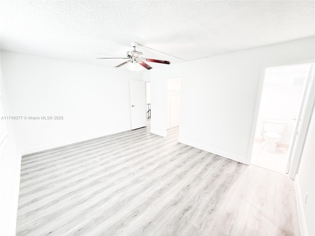 unfurnished room featuring light wood-type flooring, baseboards, a textured ceiling, and a ceiling fan