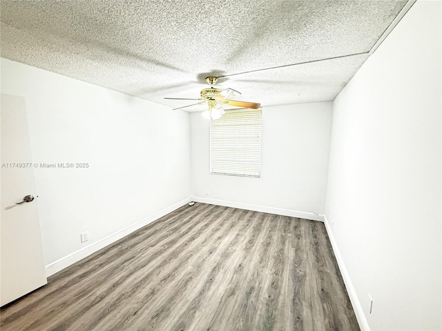 spare room featuring a ceiling fan, wood finished floors, baseboards, and a textured ceiling