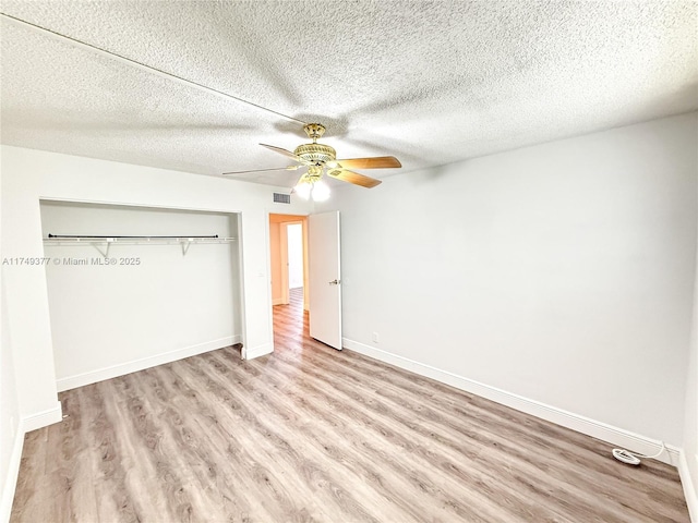 unfurnished bedroom featuring visible vents, ceiling fan, baseboards, wood finished floors, and a closet