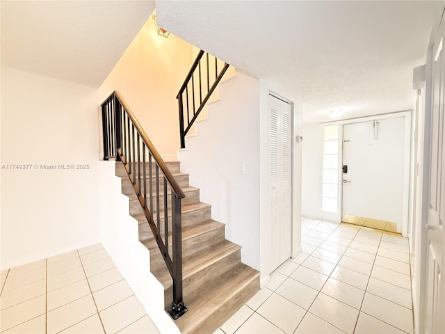 stairway featuring tile patterned floors and a textured ceiling