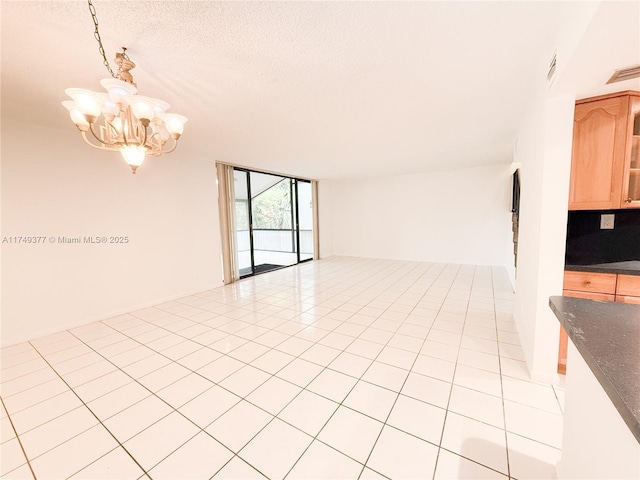 unfurnished room featuring a wall of windows, light tile patterned floors, visible vents, and a textured ceiling