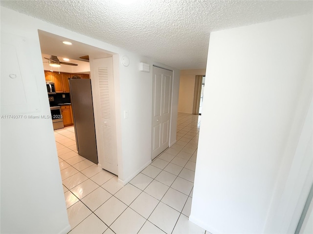 hallway featuring light tile patterned flooring and a textured ceiling