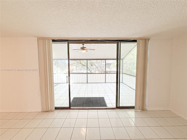 interior space with ceiling fan, a wall of windows, light tile patterned floors, and a textured ceiling