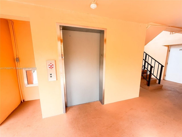 unfurnished room featuring elevator and stairway